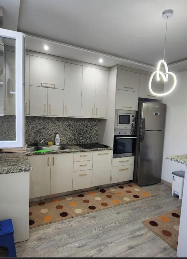 A modern kitchen with white cabinets, a stainless steel refrigerator, a microwave, and a sink. - 3-bedroom house in the amazing city of Shkodër, with all amenities included. (Shkodër)