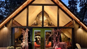 Een lodge met een stenen gevel, grote ramen en een houten dak.