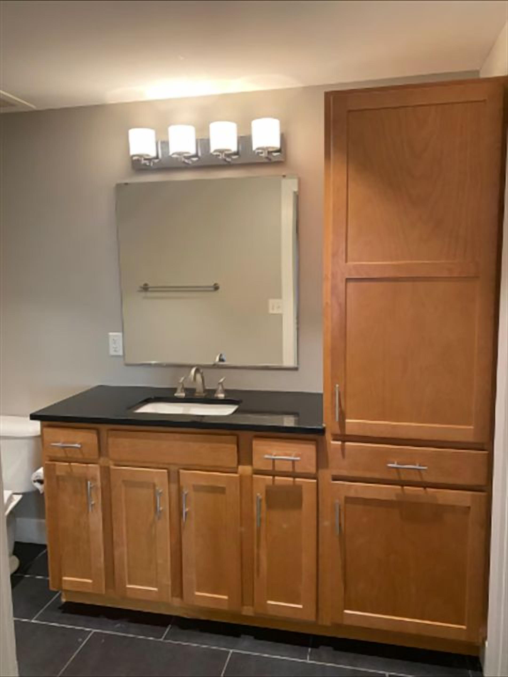 Une salle de bain avec un lavabo, un miroir et des meubles en bois.