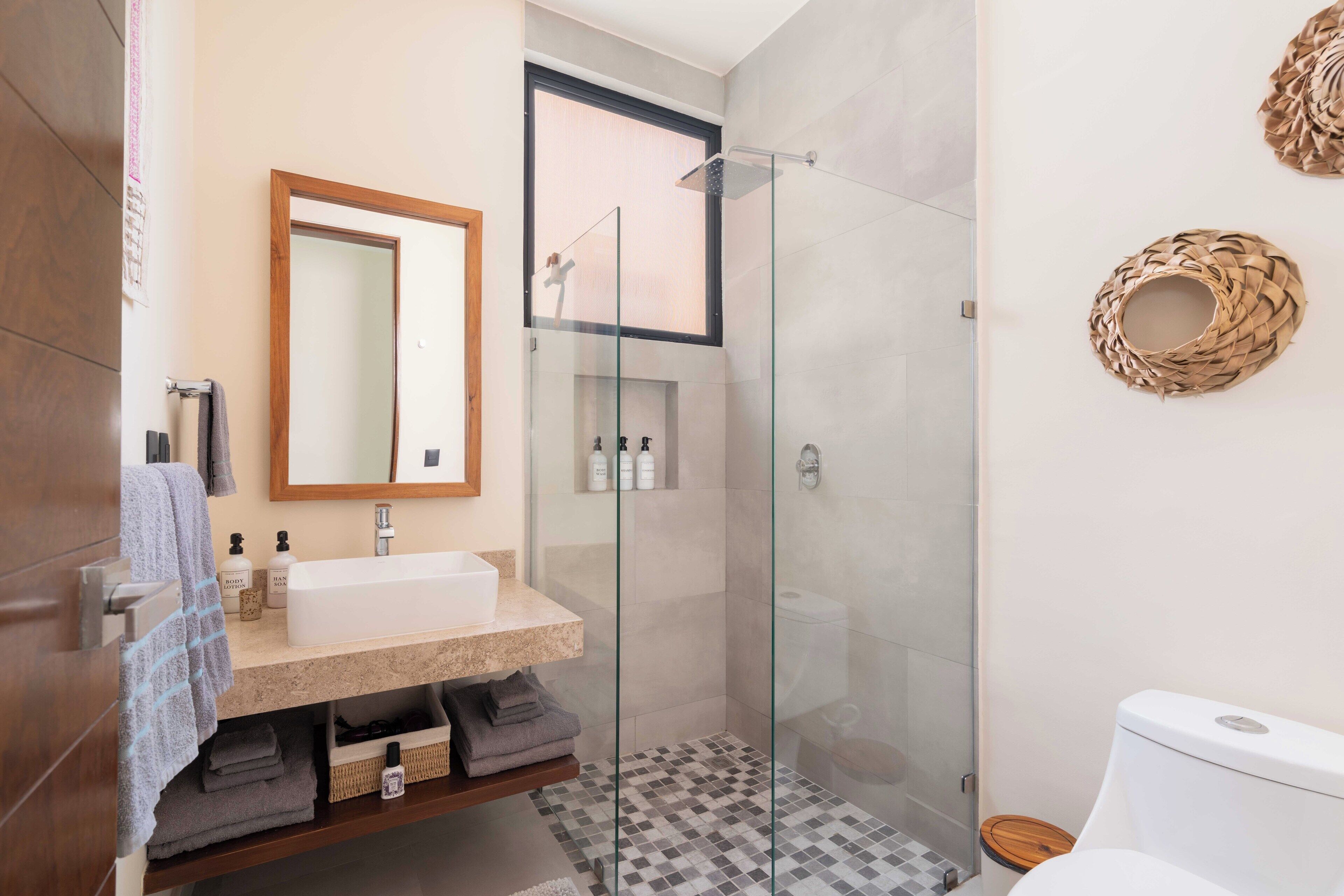 A modern bathroom with a glass shower enclosure, a vanity with a mirror, and a toilet.