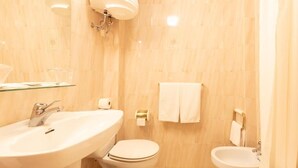 A bathroom with a sink, toilet, bidet, and a glass shelf. - HOTEL PALACIO COGOLLUDO (Cogolludo)