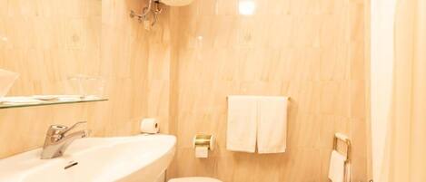 Un baño con lavamanos, inodoro, bidé y estante de vidrio.