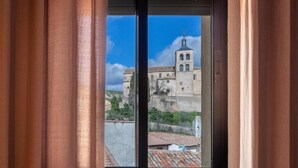 A window with a view of a historic building with a bell tower, set against a clear sky. - HOTEL PALACIO COGOLLUDO (Cogolludo)