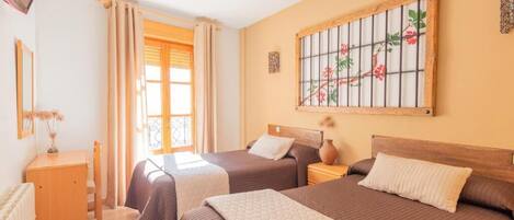 Habitación de hotel con dos camas, un televisor, una ventana con cortinas y un adorno en la pared.