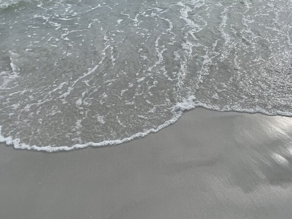 Una playa arenosa con olas acercándose a la orilla.