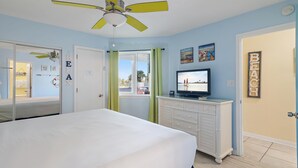 A bedroom with a bed, a ceiling fan, a television, and a dresser. - Island Sands 102 (Fort Walton Beach)