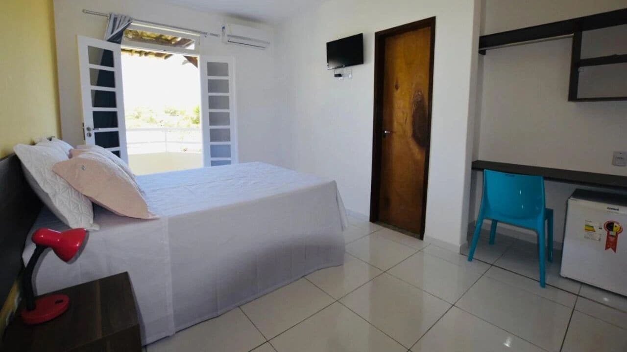 Un dormitorio con cama, escritorio, silla y puerta.