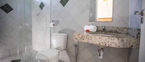Un baño con cabina de ducha de vidrio, inodoro blanco y lavamanos con encimera de granito.