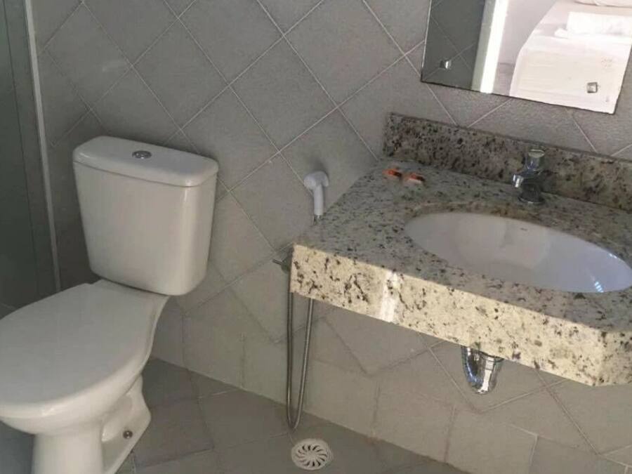 A bathroom with a toilet, a sink, and a mirror.