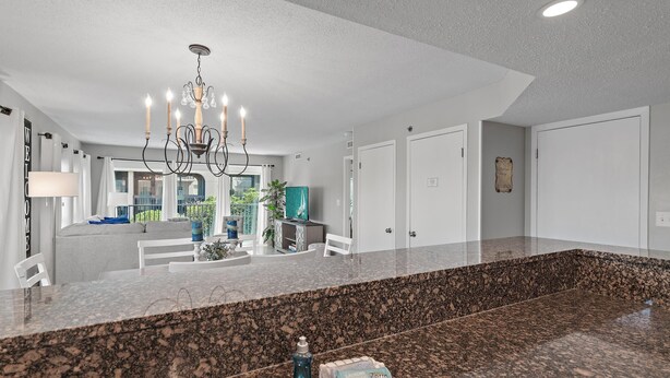A spacious kitchen with granite countertops, a chandelier, and a view of the backyard. - Sea Oats 212 (Fort Walton Beach)