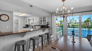 Una cucina moderna con angolo bar, mobili bianchi e vista su una piscina.