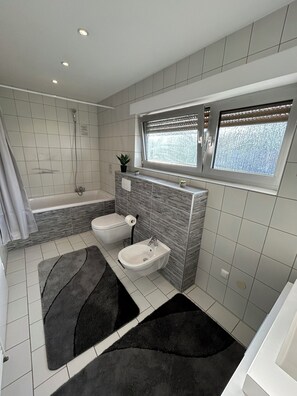 Un baño moderno con bañera, dos lavamanos, inodoro y ducha.