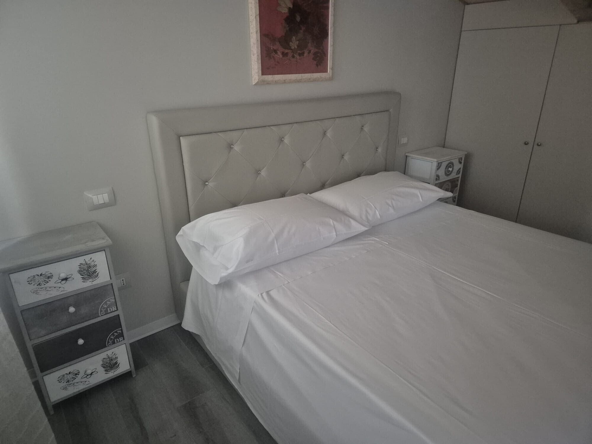 Una camera da letto con un letto, un comodino, una cassettiera e un armadio.