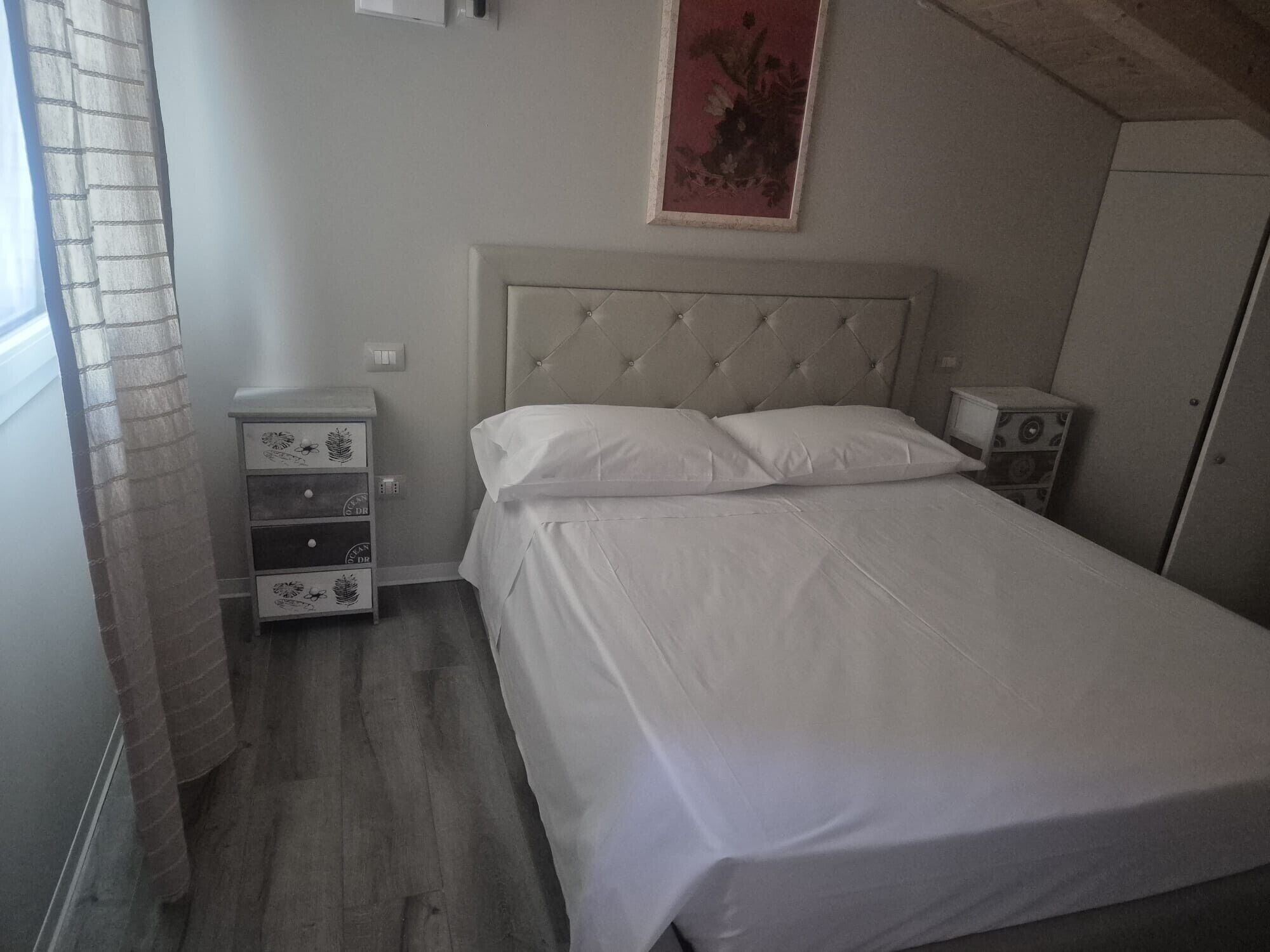 Ein Schlafzimmer mit Bett, Nachttisch, Kommode und einem Bild an der Wand.