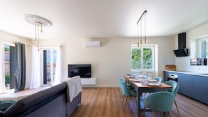 Una cocina moderna con comedor, televisor integrado y un amplio ventanal.