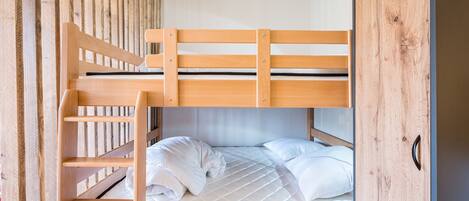 A bunk bed with a wooden headboard and a mattress with white bedding.