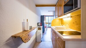 Une cuisine compacte avec des meubles en bois, un four à micro-ondes encastré et un petit réfrigérateur.