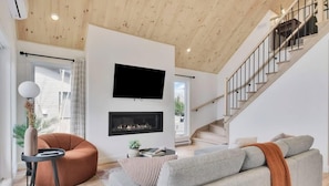 Un salon moderne avec une cheminée, un téléviseur à écran plat et un escalier.