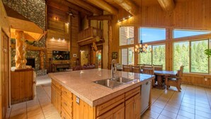 Un'ampia cucina con un'isola grande, mobili in legno e una parete decorativa in pietra.