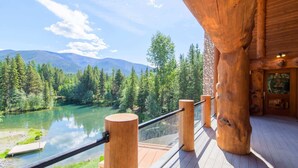 Un pontile di legno con ringhiera che si affaccia su un lago e montagne boscose.
