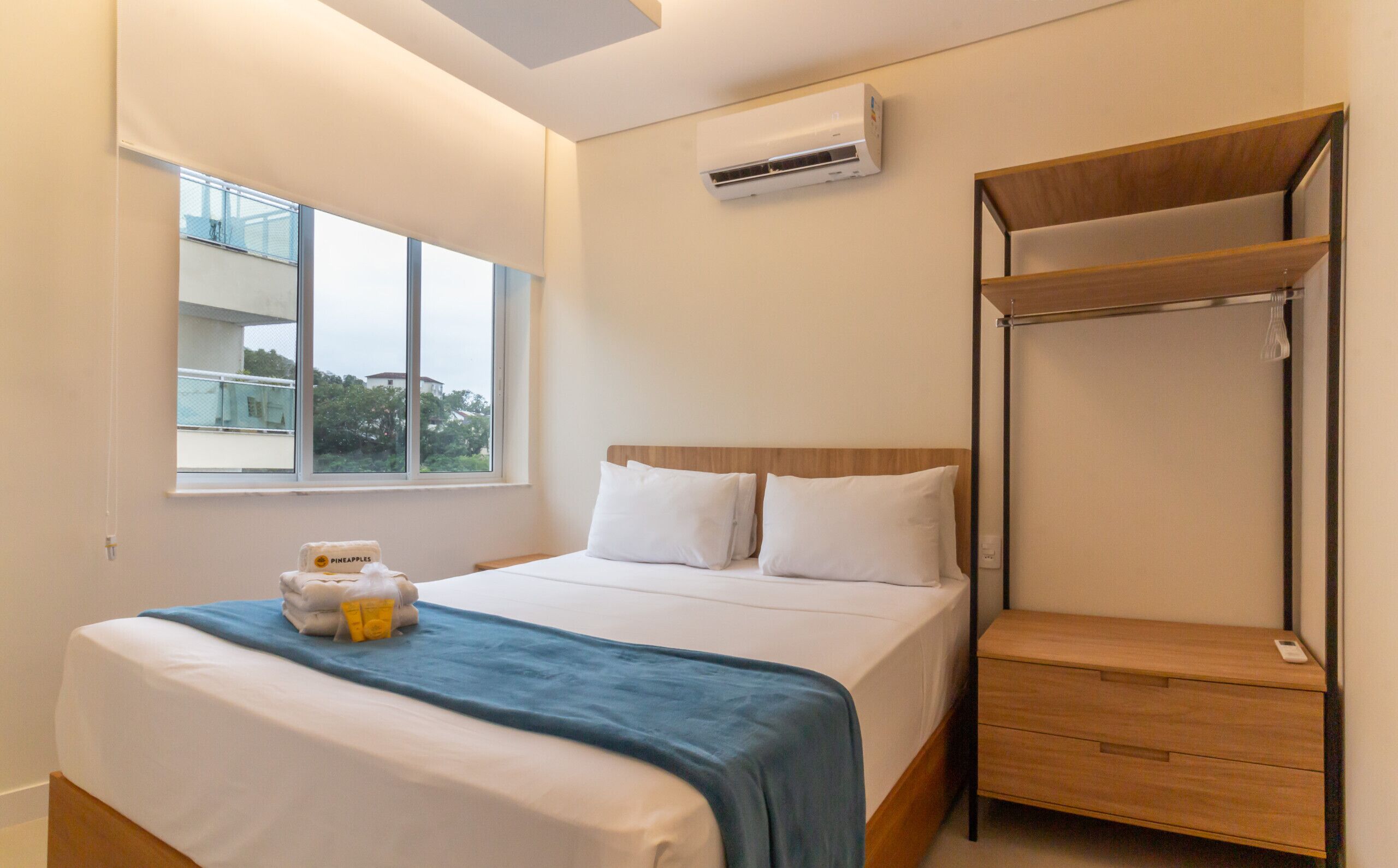 Ein Hotelzimmer mit Bett, Fenster, Klimaanlage und einem Holzschrank.