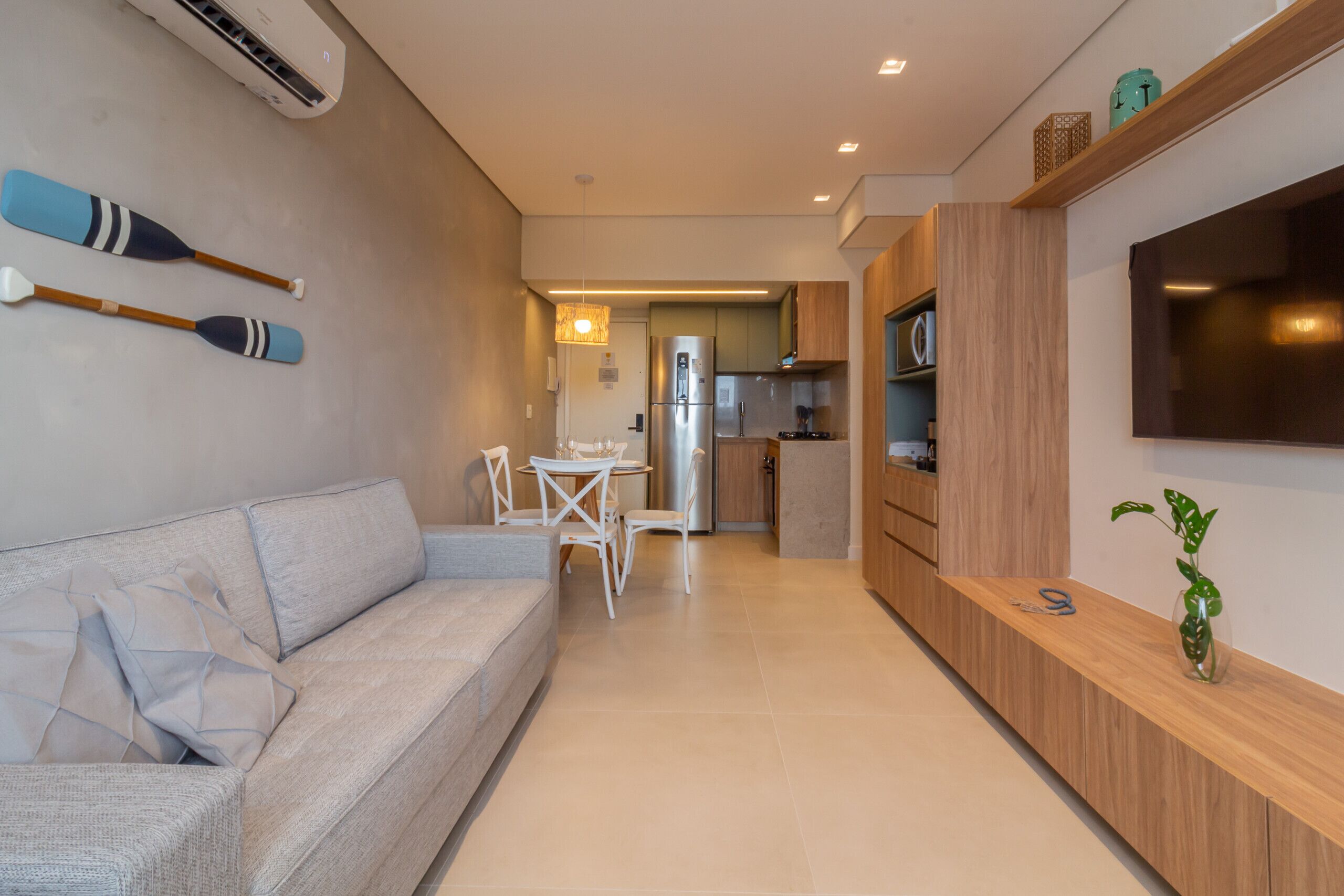 Una sala moderna con sofá, una mesa de comedor y sillas. Hay una zona de cocina con refrigerador y microondas.