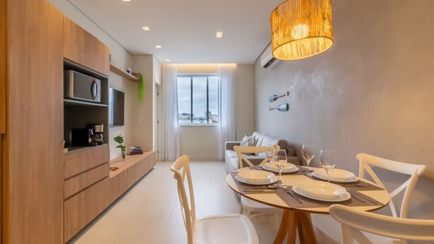 Una cucina moderna con mobili in legno, un'area pranzo con sedie bianche e un'ampia finestra con tende.