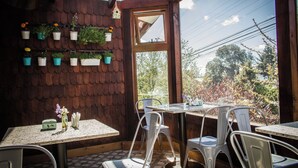 L’intérieur d’un restaurant avec des murs en bois, une grande fenêtre et de nombreuses tables et chaises.