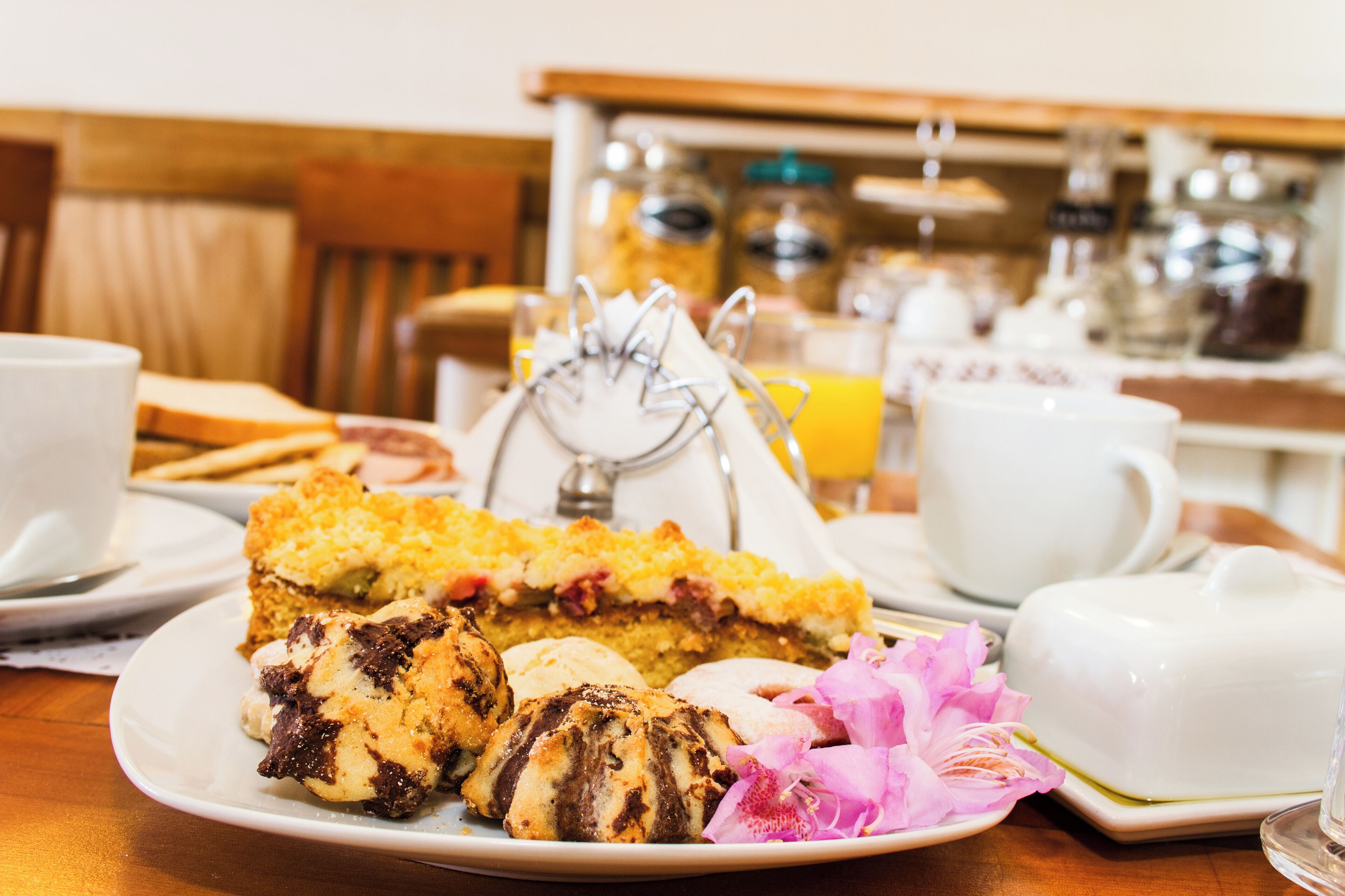 A breakfast setting with pastries, a teapot, and a coffee pot on a table.