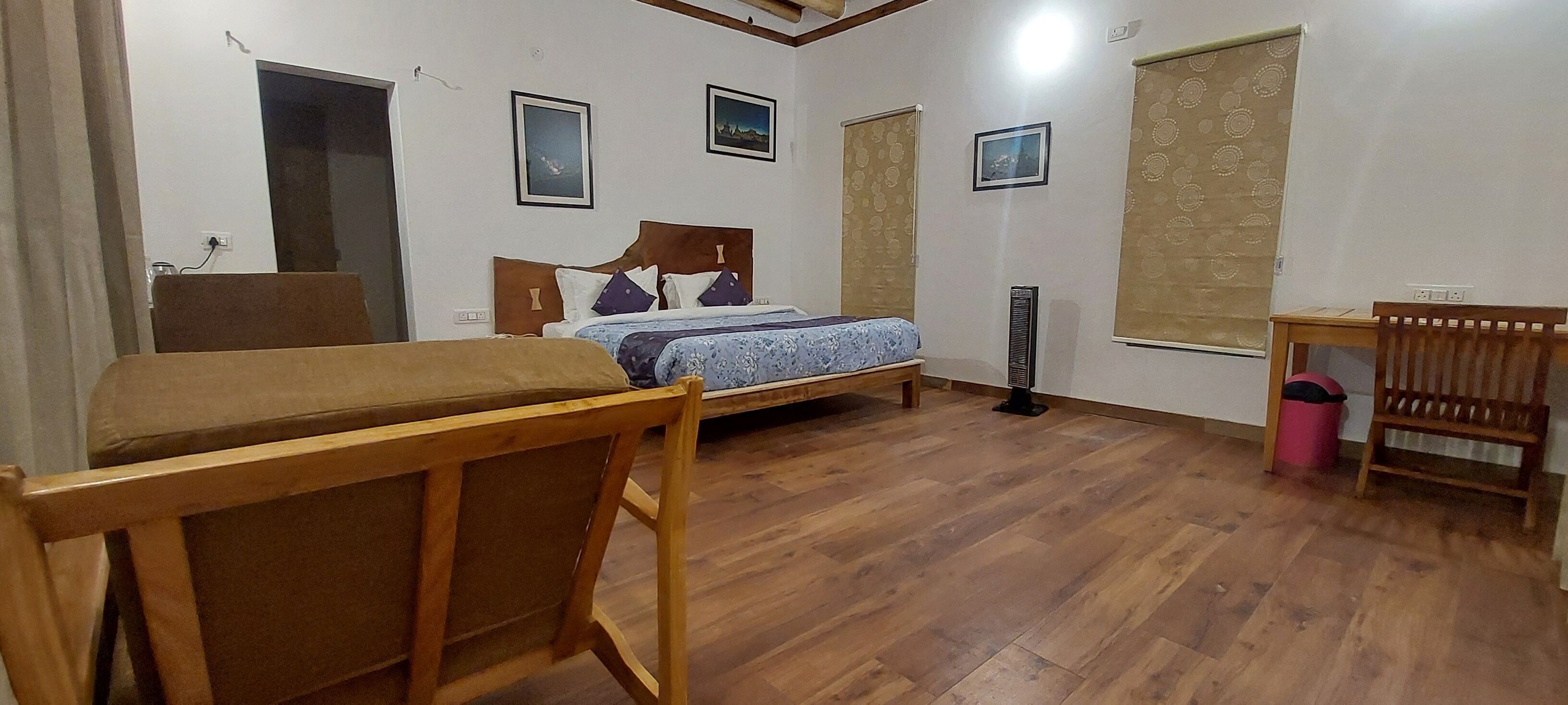 A room with a bed, a desk, a chair, and a standing heater.