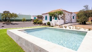 A rectangular swimming pool with a stone facade and green shutters, surrounded by a well-maintained lawn and a small garden area with various plants. - Home2Book Rural House with Private Pool & BBQ (El Rosario)