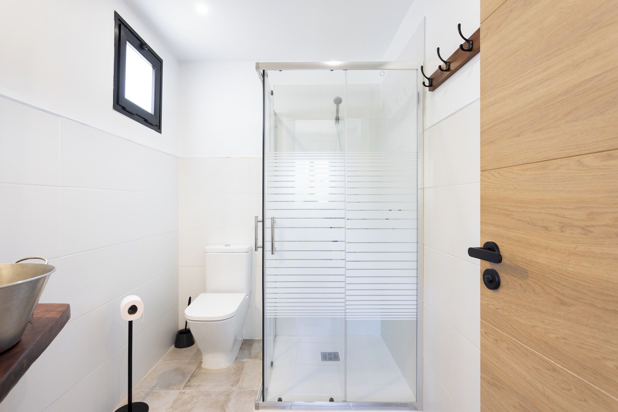 A modern bathroom with a glass-enclosed shower, a toilet, and a wooden vanity with a bowl.
