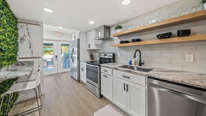 A modern kitchen with white cabinets, stainless steel appliances, and a wooden countertop. - Walk to Beach, 2 Master Beds, Newly Renovated, Walk to Restaurants, Sleeps 8 (Cocoa Beach)