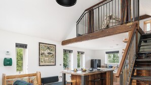 A spacious kitchen with a wooden staircase, a dining area, and large windows.