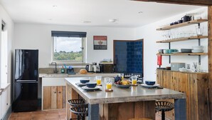 A modern kitchen with a central island, wooden cabinetry, and a view of the outdoors.