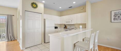 A modern kitchen with white cabinetry, a central island with bar stools, and a dining area.