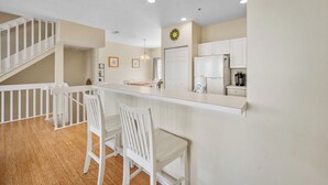 A modern kitchen with a central island, white cabinetry, and a staircase leading to another level. - Wonderful townhouse located directly between the beach and the bay.  Watch the sunsets off the balco (BRADENTON BEACH)