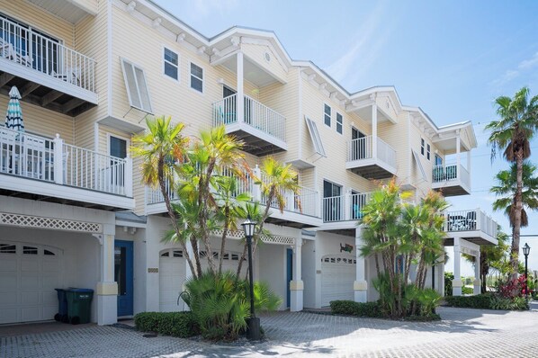A multi-story hotel with balconies, palm trees, and a cobblestone driveway.