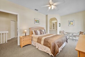 A bedroom with a bed, nightstand, desk, chair, and a ceiling fan.