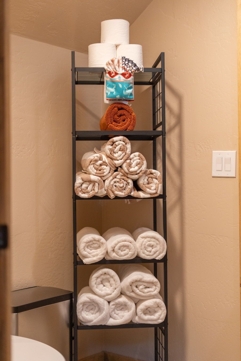 A metal shelf with towels and toilet paper.