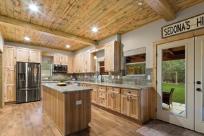 A kitchen with wooden cabinets, a stainless steel refrigerator, and a stone countertop.