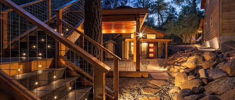 A wooden staircase with glass railings leading to a wooden deck.
