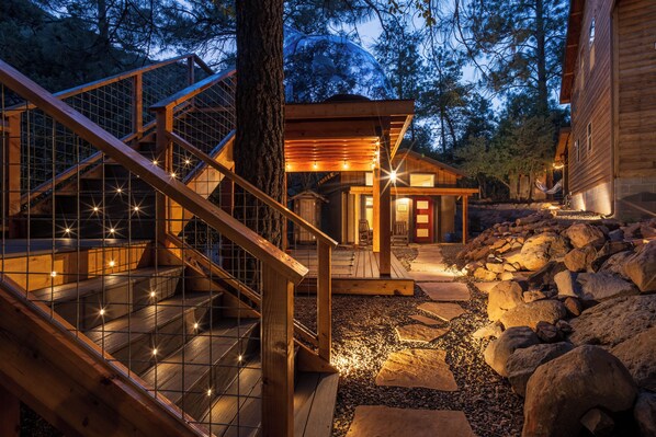A wooden staircase with glass railings leading to a wooden deck.