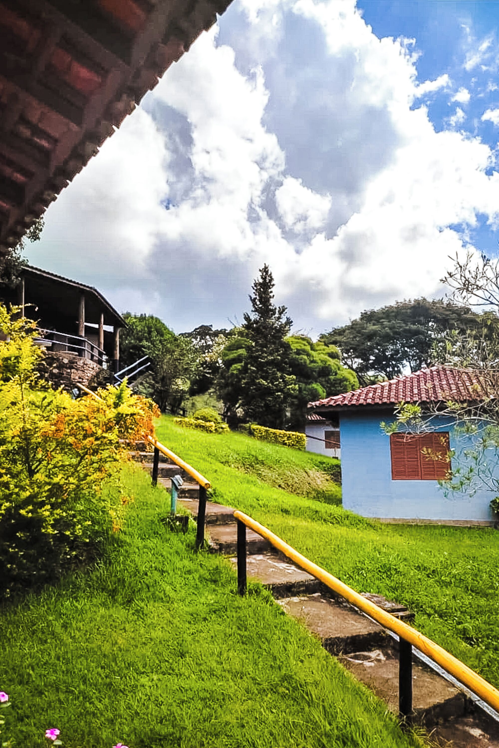 A rural setting with a blue house, a stone pathway, and a yellow pipe.