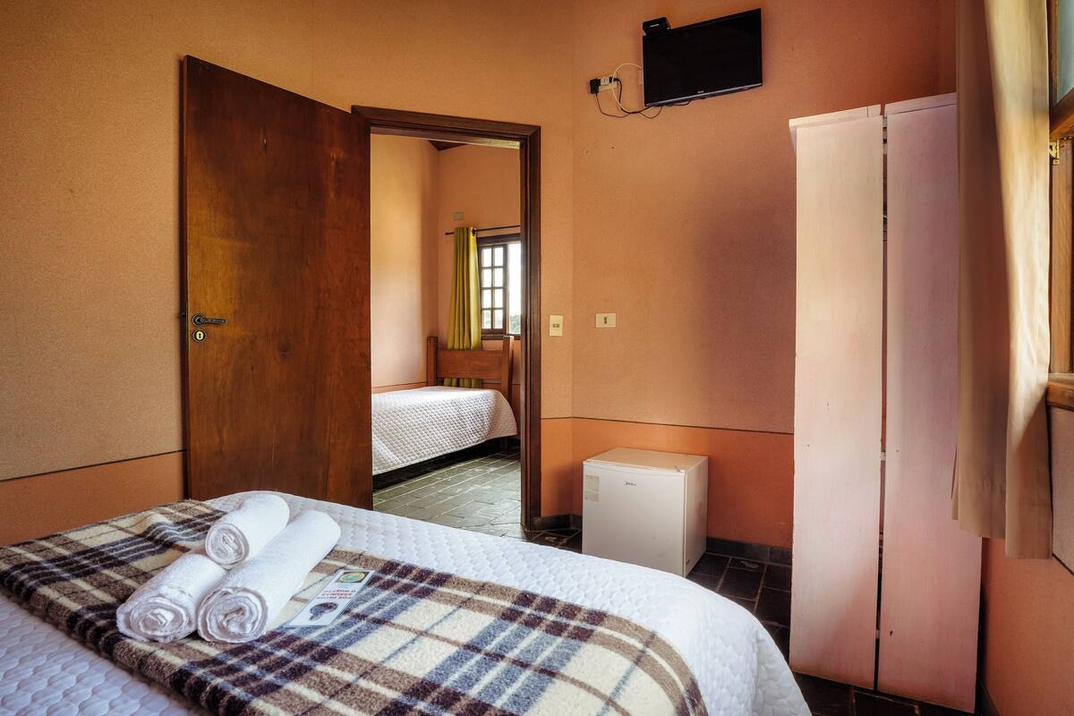 Ein Hotelzimmer mit einem Bett, einem Kleiderschrank, einem kleinen Heizgerät und einem Fernseher an der Wand.
