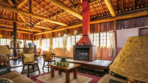 A rustic interior with a fireplace, wooden furniture, and large windows.