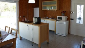 Una cocina compacta con armarios de madera, un microondas, una cafetera y un lavabo.