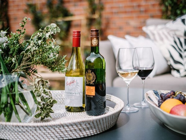 Une table avec deux bouteilles de vin, deux verres et un saladier de fruits.