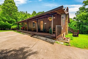 A rustic cabin with a porch, a staircase, and a small garden area. - Peaceful Path-Smoky Mountains, TN with Hot Tub (Sevierville)