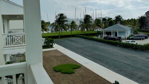 Vista de un hotel con balcón, zona de estacionamiento y un edificio pequeño con techo.